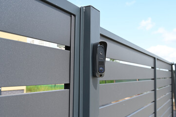 Black intercom call panel on a mounted in panel fence in anthracite color, visible wicket.Entrance...