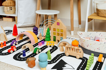 A toy town built in a children's room. Road, cars, trees and wooden blocks for children's  games in playroom. Educational game for baby and toddler in modern nursery.