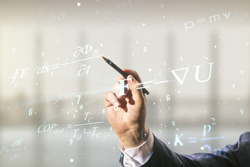 Double exposure of male hand with pen working with scientific formula hologram on blurred office...
