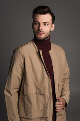 Obraz premium Portrait of man in turtleneck and autumn jacket standing isolated on grey.