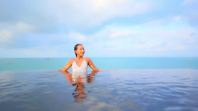 Happy Exotic Woman in Infinity Swimming Pool With Tropical Sea Horizon in Background