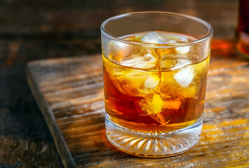 Close up of A glass of liquor with ice cubes on a wooden table