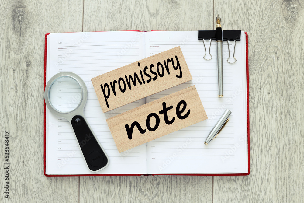 Poster promissory note. wooden blocks with text. on a red notebook