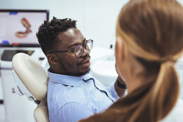 Obraz premium Black guy patient with open mouth having dental treatment from female doctor, close up. Man and female doctor while checkup teeth. Healthy lifestyle, healthcare and medicine concept.