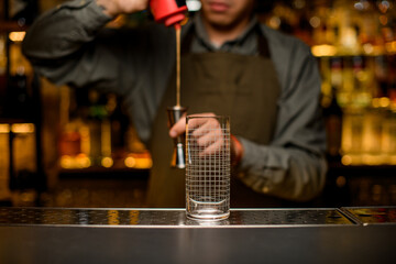 Front view of clean transparent empty glass with grid pattern on bar. Blurred background