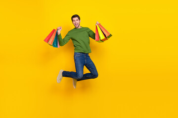 Photo of pretty lucky guy wear green sweater jumping rising shoppers empty space isolated yellow color background