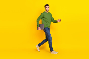 Fototapeta na wymiar Photo of sweet attractive guy dressed green pullover walking holding modern gadget isolated yellow color background