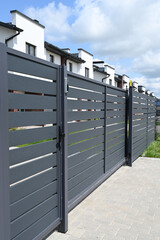 High grey fence. Modern barrier aluminum slats. Modern stone fence with metal shutters
