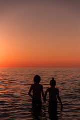 Silhouette of a girl and a boy. Children at   sunset at the beach