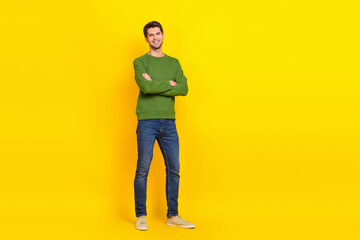 Fototapeta na wymiar Photo of pretty charming guy wear green sweater arms crossed empty space isolated yellow color background