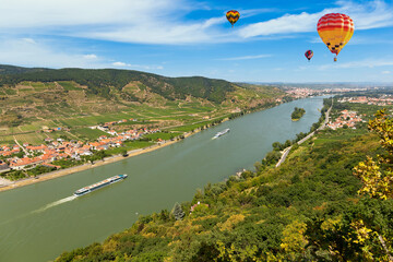 Hot air balloons in the sky over the Danube river in the Wachau valley.