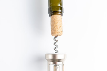 Close-up of a corkscrew opening a bottle of wine. The cork is pierced by the black metal spiral of...