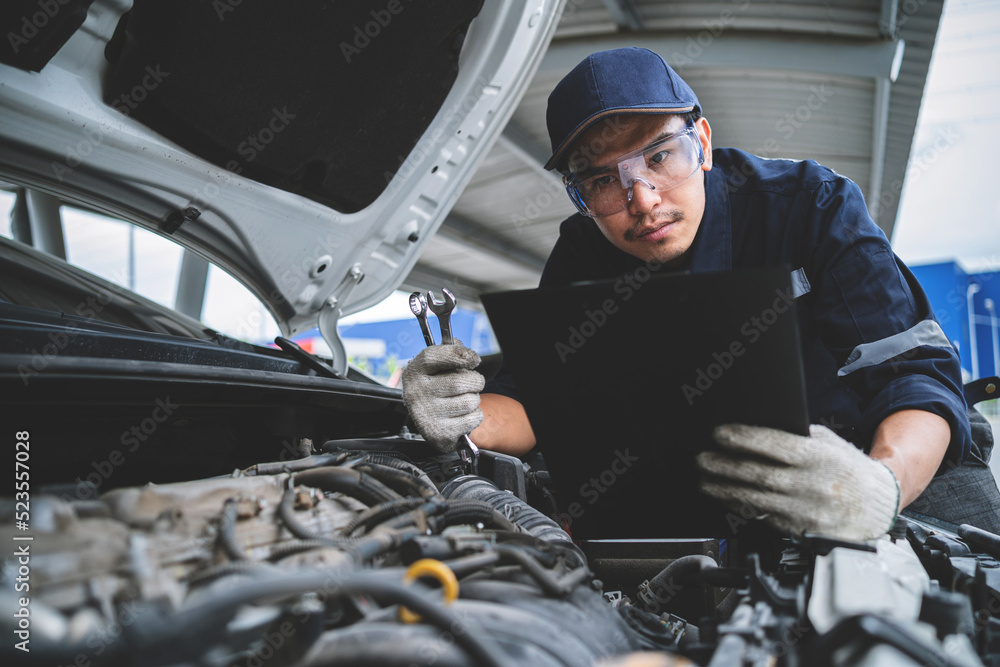 Wall mural Portrait of an Asian mechanic checking the safety of a car. Maintenance of damaged parts in the garage. Maintenance repairs. Repair service concept. - Wall murals