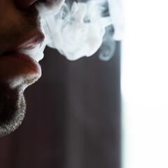 Seductive male lips blowing cigarette smoke.
