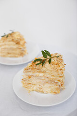 Piece of Napoleon cake on a white saucer isolated on a white background. Cake of puff pastry with sour cream. Copy space.