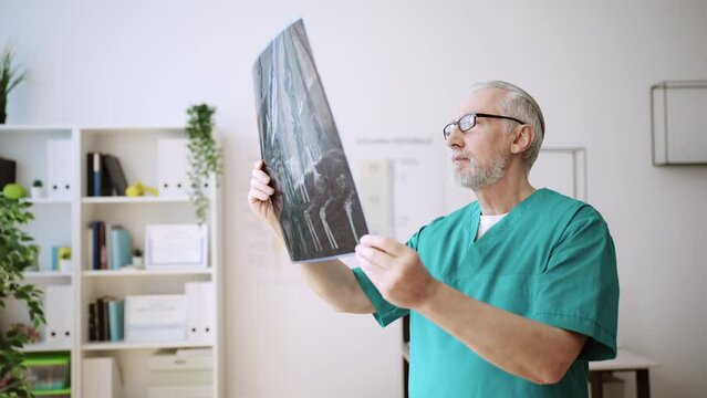 Male doctor examining x-ray picture of his patient, diagnostic center, health