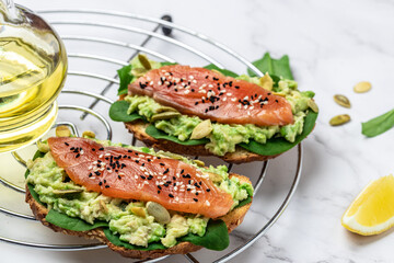 Delicious breakfast or snack sandwich salmon, avocado, spinach, nuts, sunflower seeds, toast with red fish and guacamole. Healthy, clean eating. Vegan or gluten free diet. top view, copy space