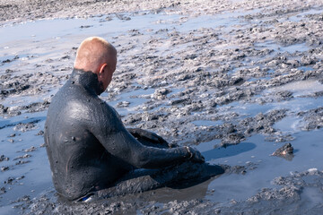 Fototapeta premium A man applies healing mud to his body. Beneficial effect on the body and skin. Healthcare. Salt and mud from the Dead Sea