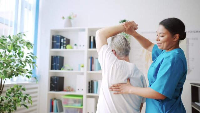 African American physiatrist examining patient's arm, therapeutic exercises