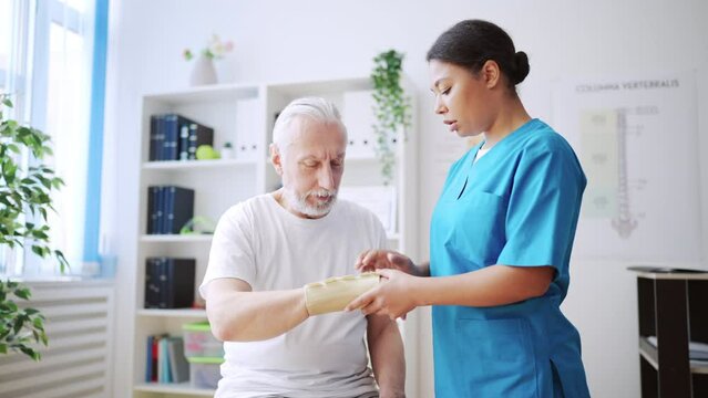 Female traumatologist putting cast on patient's arm, bone fracture treatment