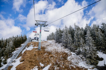 Naklejka premium Dolni Morava, Czech Republic, 16 April 2022: Path in the clouds, tourist attraction, spiral platform to observation tower, landscape with forest and sky on mountains, Skywalk with snow, mountain lift