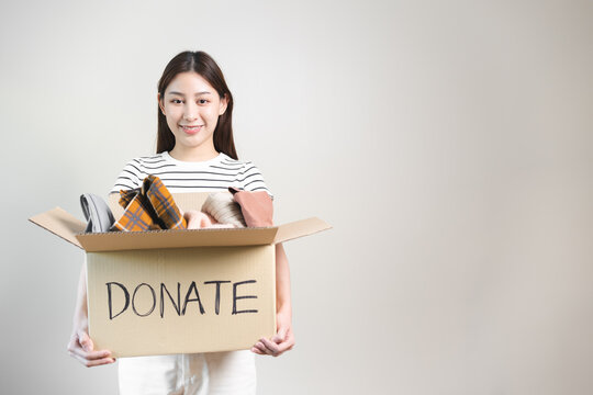 person separate clothes for donation into boxes and wait to give to volunteer charity to share to another people.