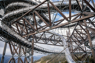 Obraz premium Dolni Morava, Czech Republic, 16 April 2022: Path in the clouds, tourist attraction with spiral platform to observation tower, landscape with forest and sky on mountains, Skywalk with snow