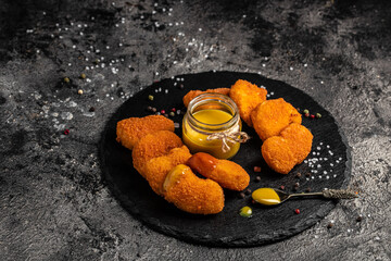 Fried crispy chicken nuggets with mustard honey sauce on stone board, american unhealthy calories...