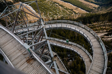 Naklejka premium Dolni Morava, Czech Republic, 16 April 2022: Path in the clouds, tourist attraction with spiral platform to observation tower, landscape with forest and sky on mountains, Skywalk with snow