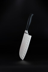 Chef's steel kitchen knife on black background.