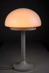 modern desk lamp with mushroom shape spaceage vintage midcentury design front side view white black background with warm orange light isolated in the studio living room creative HIGH RESOLUTION