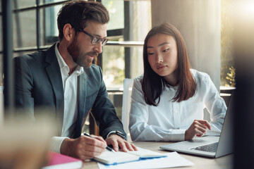 Two focused business people working in a modern office and discussing a new project