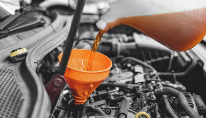 Concept changing motor oil in car engine at garage service station. Closeup move yellow lubricant