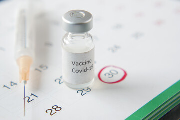 vaccine day concept glass ampoule with vaccine and syringe on calendar 