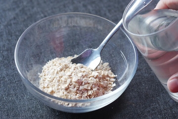 putting water in raw oats flakes in a bowl 