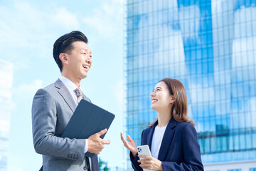高層ビルの前に立つビジネスマン男女