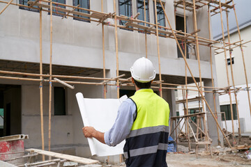 Fototapeta na wymiar Foreman checking blueprint with house construction site for good quality product