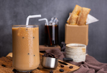  iced coffee in transparent glass and roasted coffee beans and Crispy Pie dessert on wood. black background studio  horizontal photo