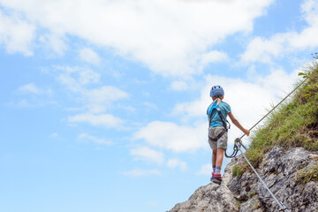 Eight-year-old girl in the via ferrata, exposed, copyspace - obrazy, fototapety, plakaty