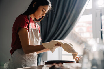 Young hispanic woman wearing apron making pie in kitchen