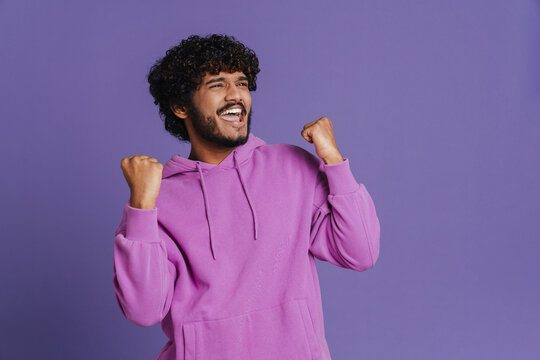 Portrait Of Young Indian Handsome Curly Celebrating Man Rasing Fists