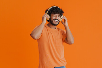 Young handsome indian smiling man in headphones enjoying music