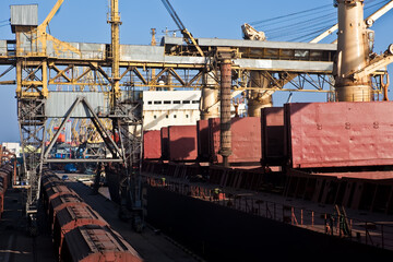 Fototapeta na wymiar Loading grain into holds of sea cargo vessel in seaport from grain storage.