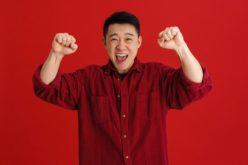 Asian excited man screaming while making winner gesture