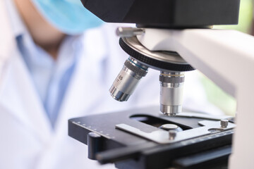 Scientist analyzing microscope slide at laboratory. Young woman technician is examining a histological sample, a biopsy in the laboratory of cancer research