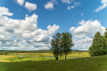 Fototapeta na wymiar Background of a blue sky with clouds, a green field, river and forest
