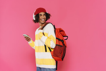 Young caribbean man in headphones smiling and using cellphone