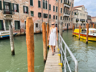 Fototapeta na wymiar Woman wearing white dress walking on the pier in Venice