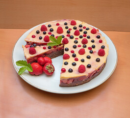 whole grain fruit cake with pudding and variety of berries, wooden background