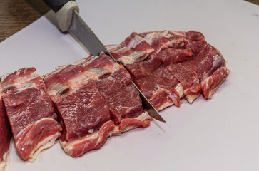 Butcher cuts lamb fillet with a knife on a cutting board	
